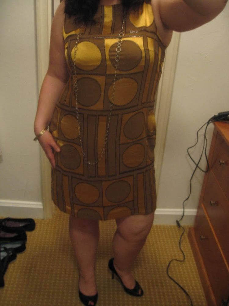 Woman wearing a gold and olive graphic print silk shift dress