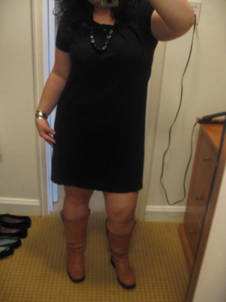 Woman in a black sweater knee length dress and tan knee high boots