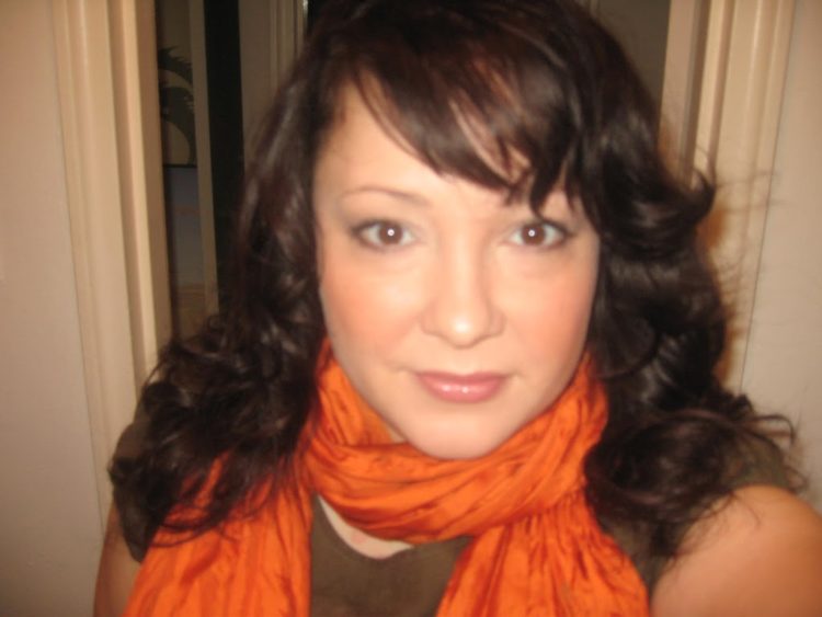 Alison Gary wearing smoky gray eyeshadow and an orange crinkle silk scarf looped around her neck