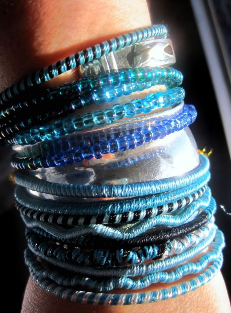 a wrist full of blue and silver bracelets