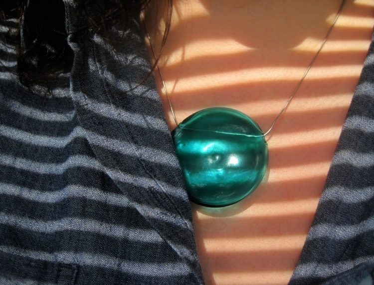 closeup of a green glass pendant on a silver chain