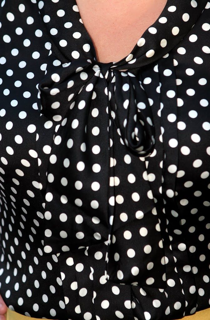 closeup of a black and white polka dot blouse with a bow detail