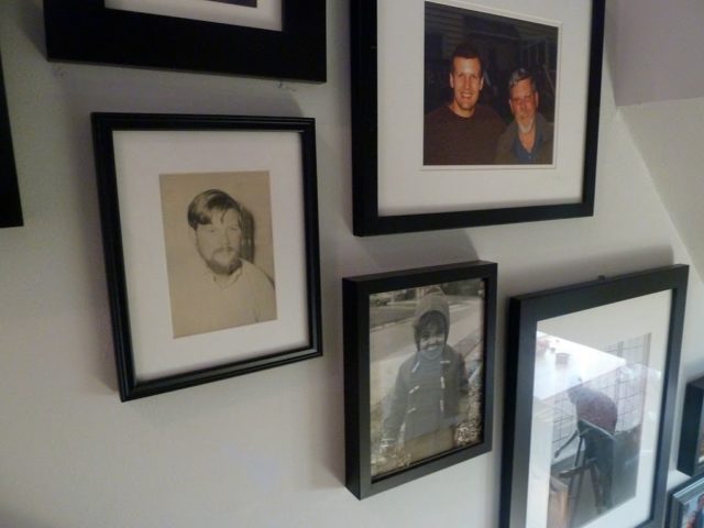 A closeup of family photos in black frames on a wall in a stairwell