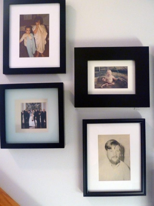 a collage of family photos in black frames with white matting in a stairwell