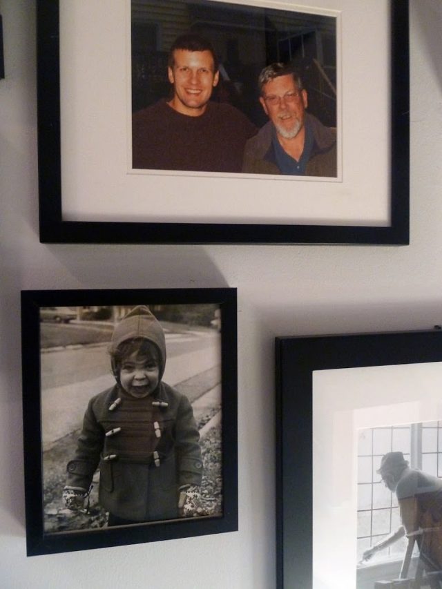 a collage of family photos in black frames with white matting in a stairwell