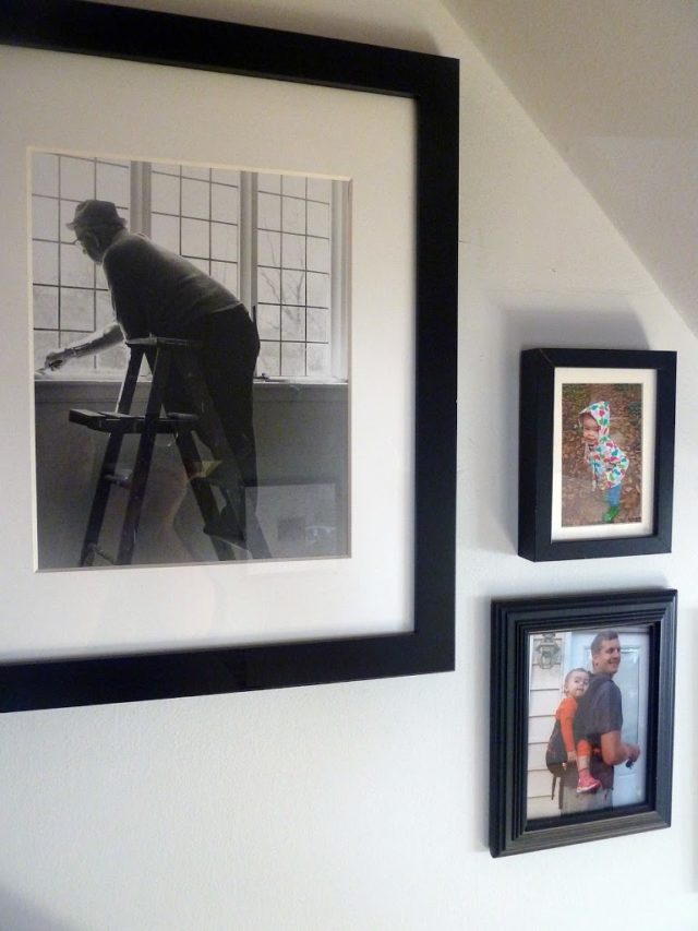 a collage of family photos in black frames with white matting in a stairwell