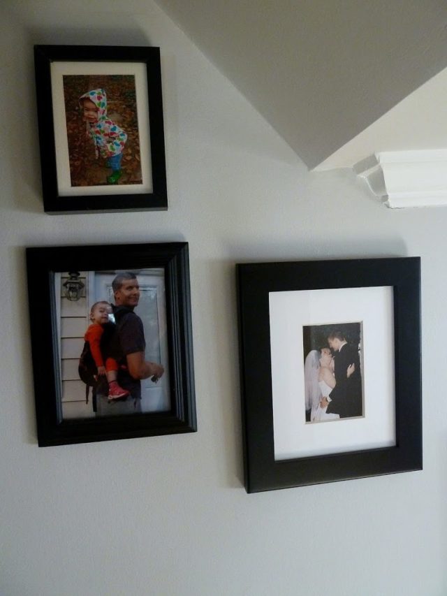 a collage of family photos in black frames with white matting in a stairwell