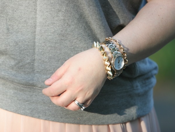 closeup of a woman's arm wearing a watch and two gold bracelets