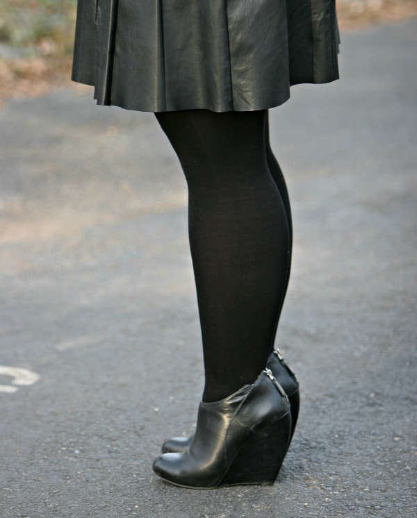 Woman's legs wearing black tights and black wedge ankle booties from Nine West