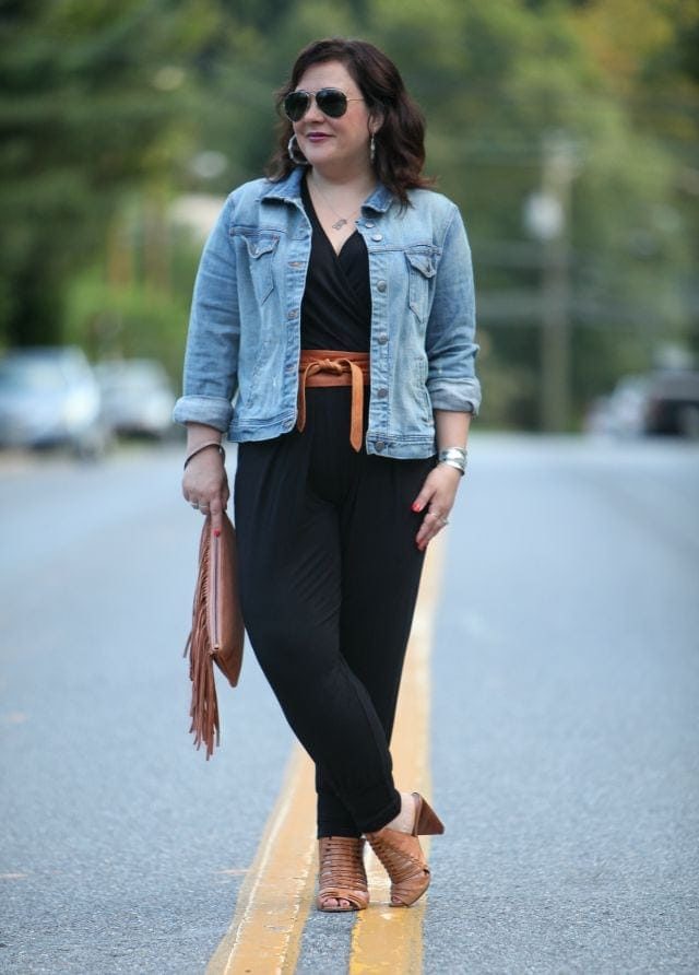 Wardrobe Oxygen wearing a J.Crew Factory denim jacket, Loveappella jumpsuit, BCBGeneration fringe clutch, and ADA Collection wrap belt