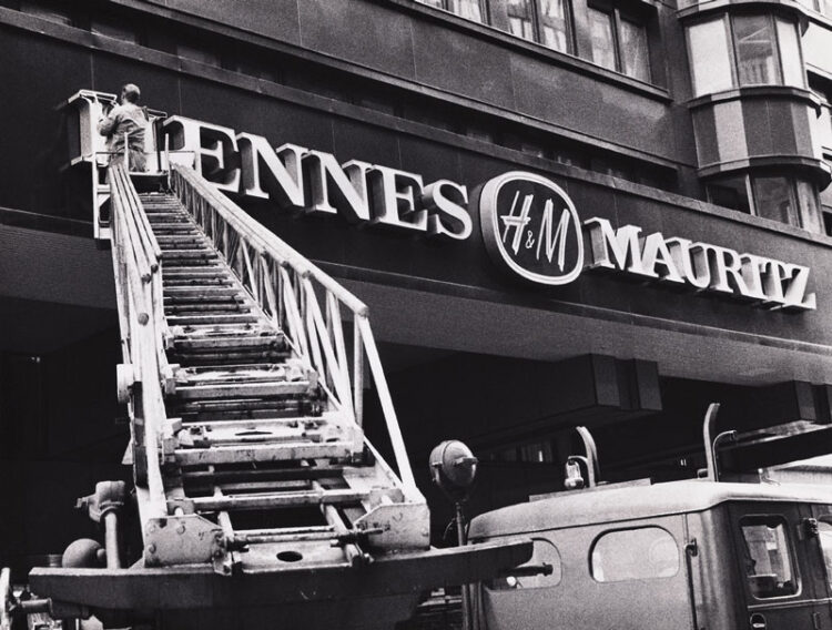 Let's Discuss Shopping at H&M in 2026 3 A ladder changing the name of a storefront from Hennes to Hennes Mauritz with the H&M logo