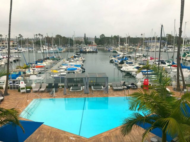 view of the marina from a window at the marina del rey hotel. in the picture are several boats in a marina and a swimming pool