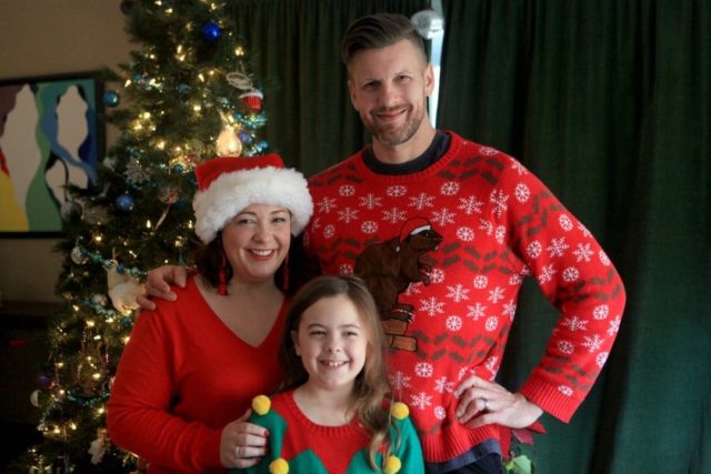 A man, woman, and young girl all in christmas sweaters