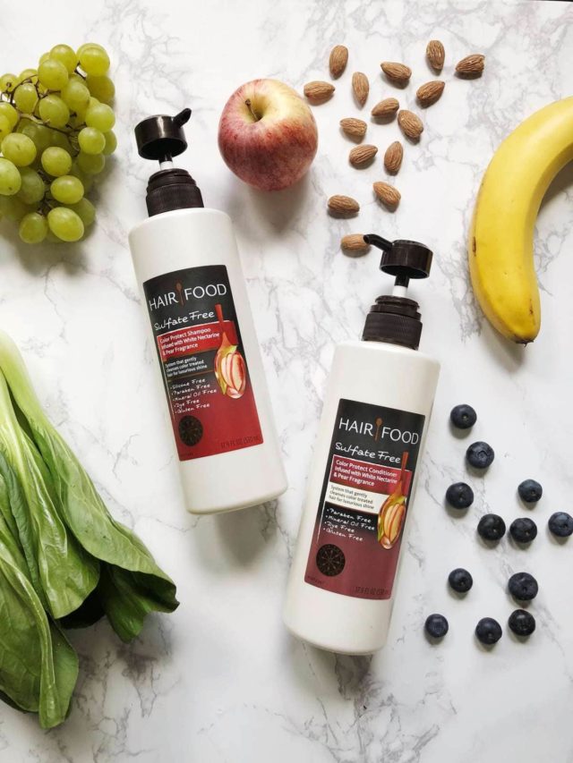 Bottle of Hair Food Color Protect Shampoo and Conditioner on a table surrounded by fruits and vegetables and nuts