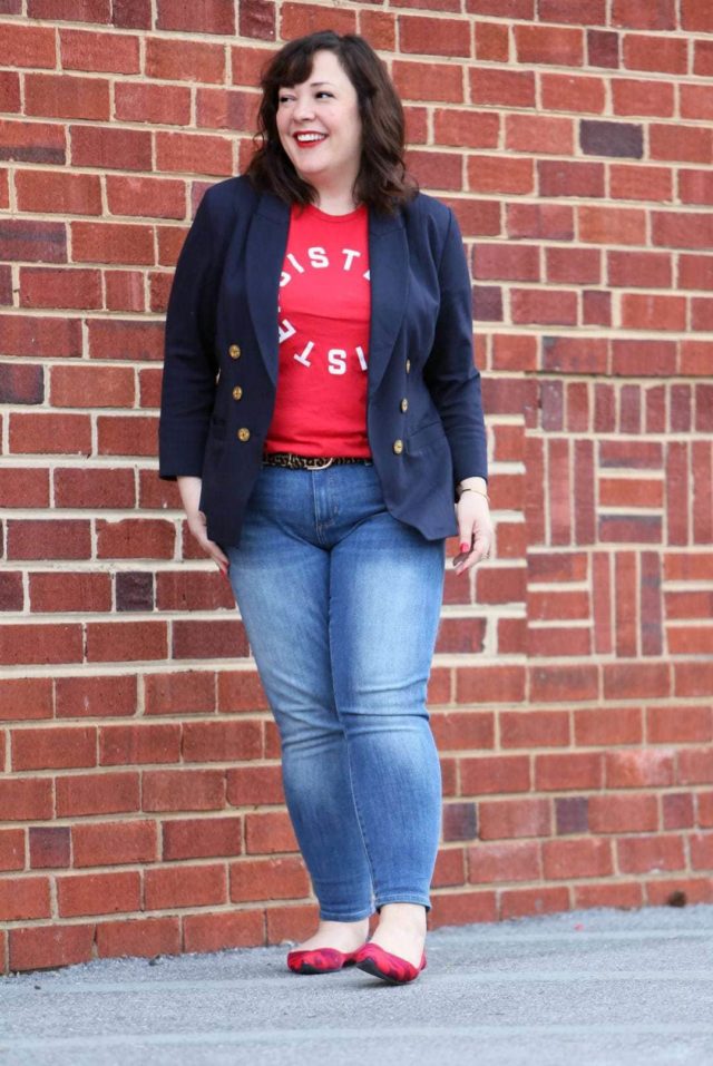 What I Wore: Resister Sister 1 Woman in front of a brick wall wearing a t-shirt that says Resister Sister on it. She is wearing a navy double-breasted blazer over it and skinny jeans on the bottom half.