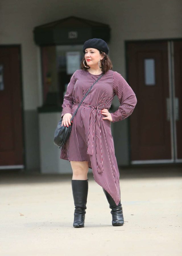 Woman in a red stripe long sleeve asymmetrical dress with a black beret, black round crossbody bag, and black knee-high boots. She is standing in front of the Greenbelt Cinema in Greenbelt, MD.