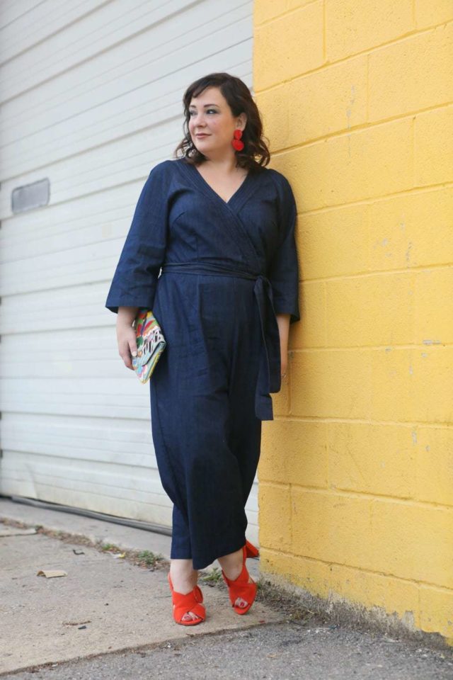 Wardrobe Oxygen in a plus size denim jumpsuit from ELOQUII with orange sandals and red lucite statement earrings - ELOQUII Denim Jumpsuit styled by popular Washington DC petite fashion blogger, Wardrobe Oxygen