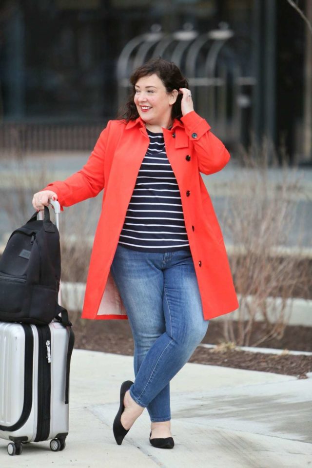 Wardrobe Oxygen in a red orange trench from Banana Republic with Talbots striped top, Banana Republic ankle jeans, Rothy's flats, Dagne Dover backpack and Delsey spinner suitcase