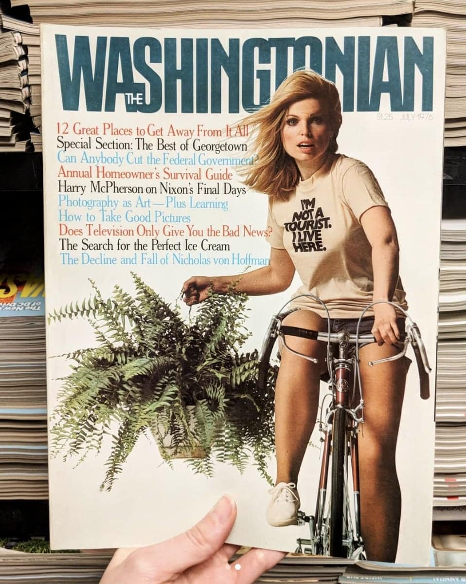 Cover of a Washingtonian Magazine. It features a blonde woman on a bicycle carrying a fern plant. She is wearing a t-shirt that says I'm Not a Tourist. I Live Here.