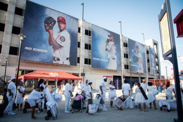 Images of individuals in white pulling carts holding tables, chairs, and dining supplies as they enter Nationals Stadium in Washington DC for Dîner en Blanc