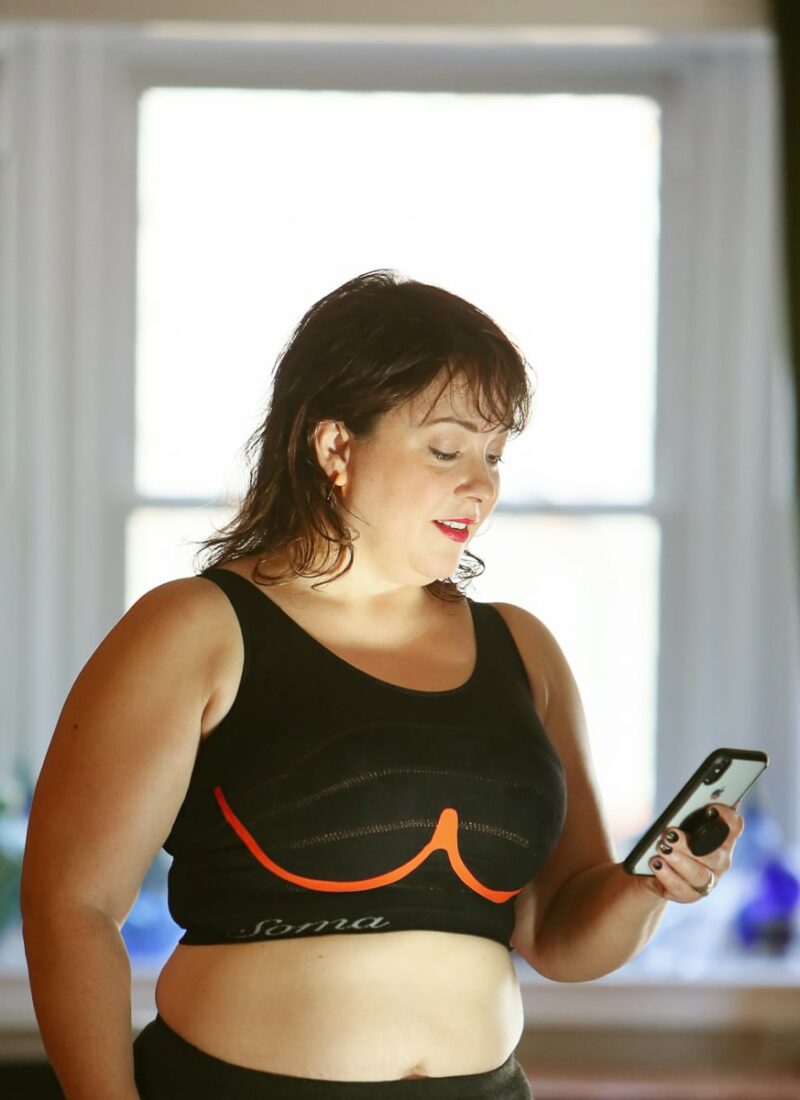 Alison wearing the Soma INNOFIT bra while looking at the INNOFIT app on her smartphone