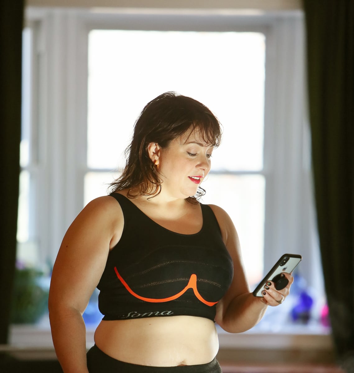 Alison wearing the Soma INNOFIT bra while looking at the INNOFIT app on her smartphone
