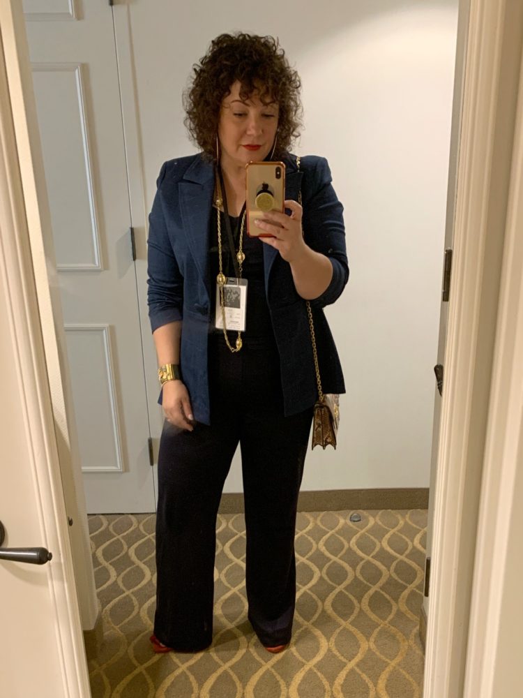 woman in navy blazer and trousers taking a mirror selfie