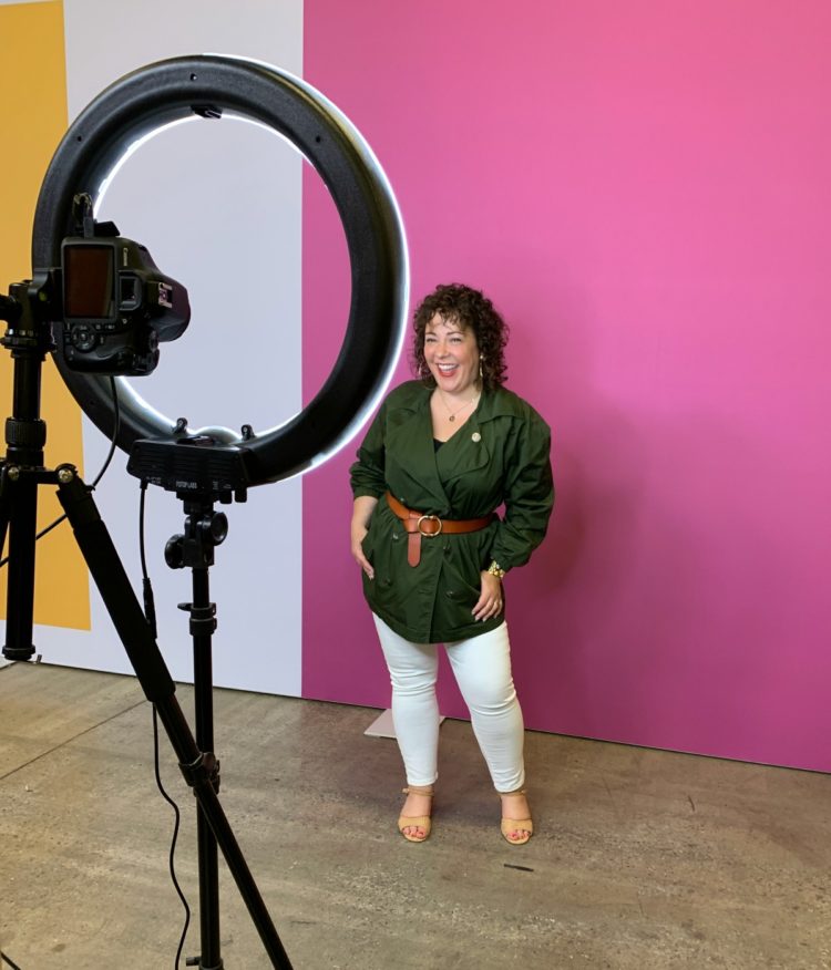 woman smiling at a camera inside of a ring light