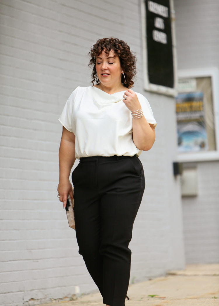 Woman in the Universal Standard Viva Boatneck Top in white with black tux-inspired ankle pants from Talbots.