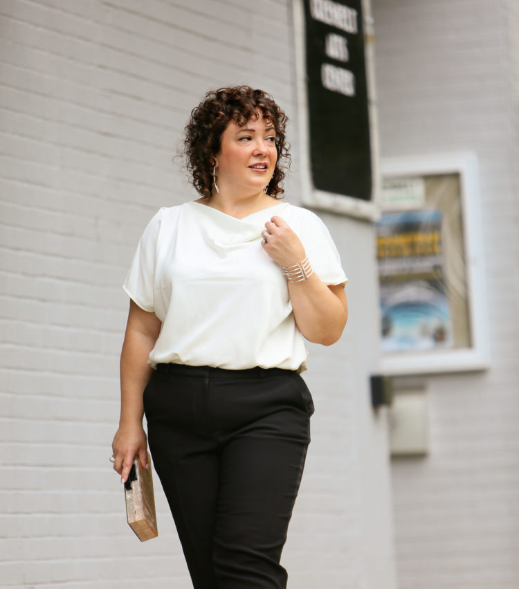 Woman in the Universal Standard Viva Boatneck Top in white with black tux-inspired ankle pants from Talbots.