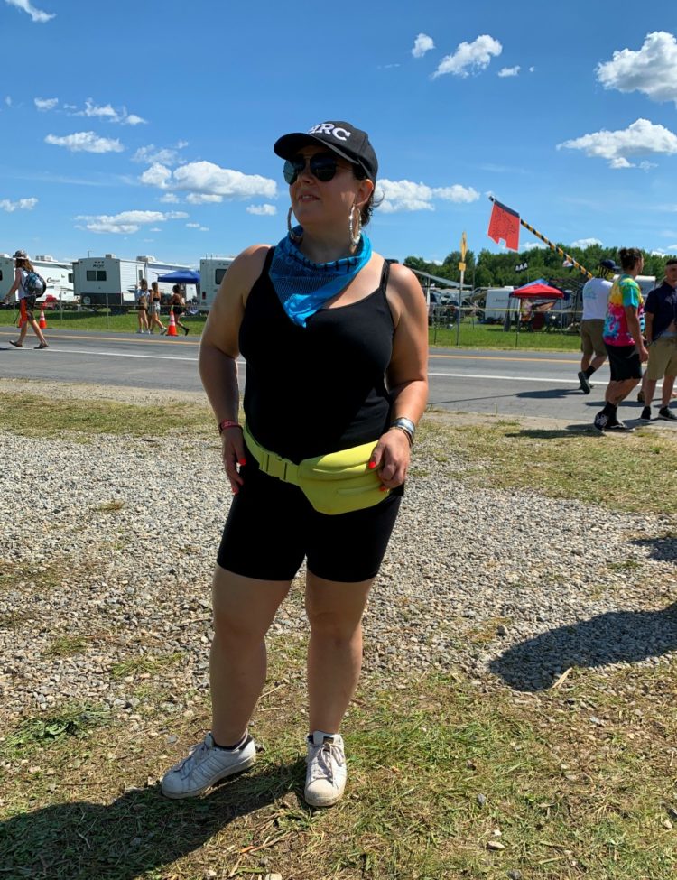 woman in black bike shorts and a fanny pack standing at the gates to the Firefly music festival