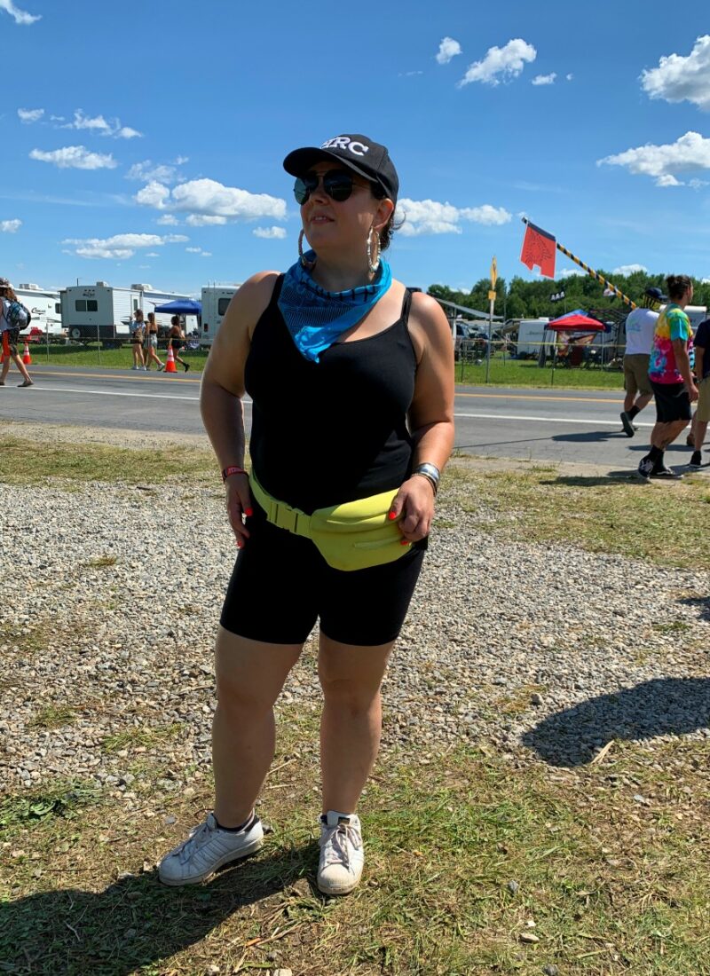 woman in black bike shorts and a fanny pack standing at the gates to the Firefly music festival