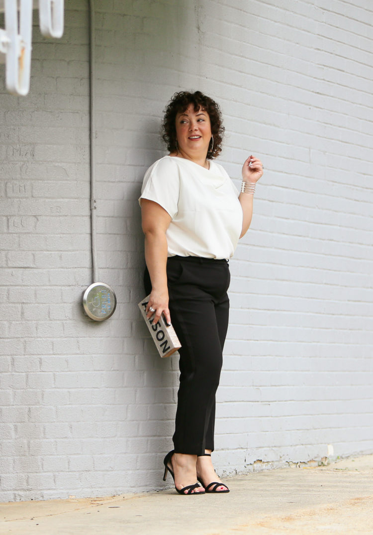 Woman in the Universal Standard Viva Boatneck Top in white with black tux-inspired ankle pants from Talbots.