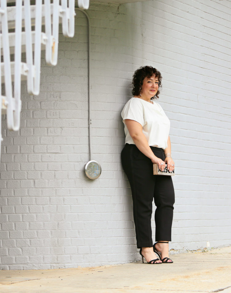 Woman in the Universal Standard Viva Boatneck Top in white with black tux-inspired ankle pants from Talbots.
