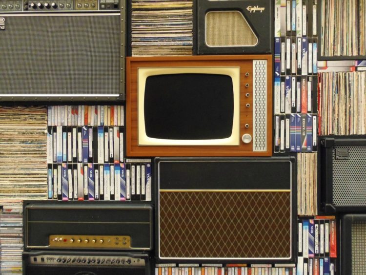 stack of CRT televisions and vintage speakers with VHS video tapes