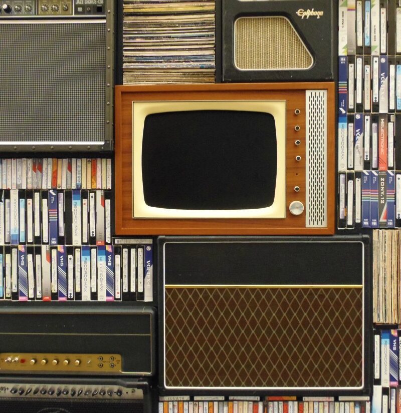 stack of CRT televisions and vintage speakers with VHS video tapes