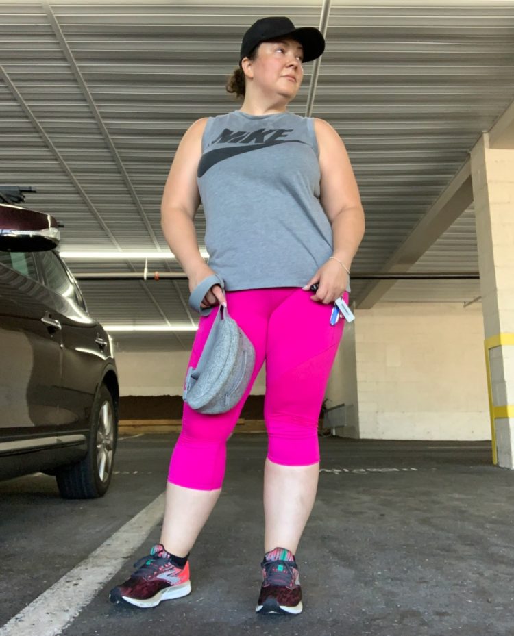 woman standing in gray sleeveless shirt and magenta leggings looking to the side