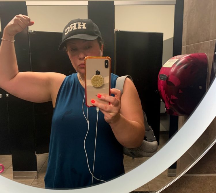 woman taking mirror selfie flexing one bicep