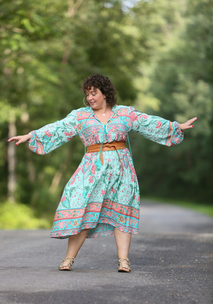 woman in a boho inspired dress with her arms out dancing