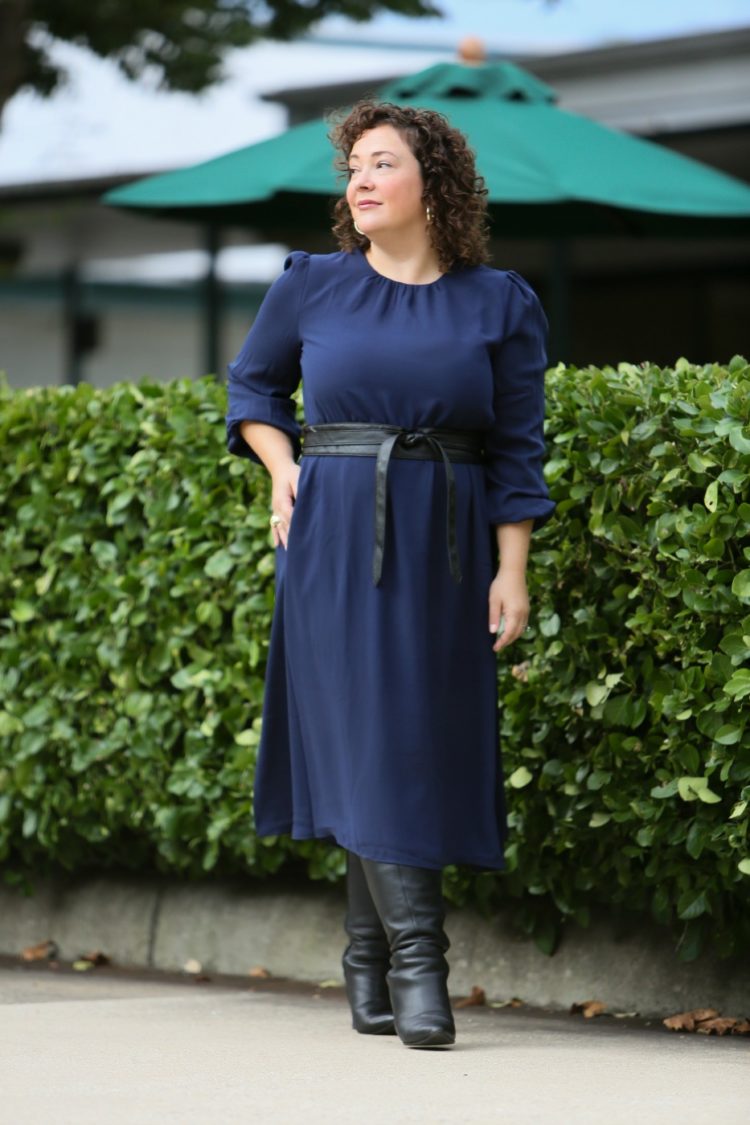 woman in a navy dress with a black leather obi belt and black heeled tall boots