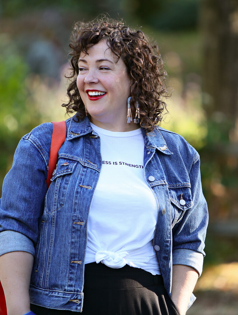 woman in denim jacket smiling and looking to her right