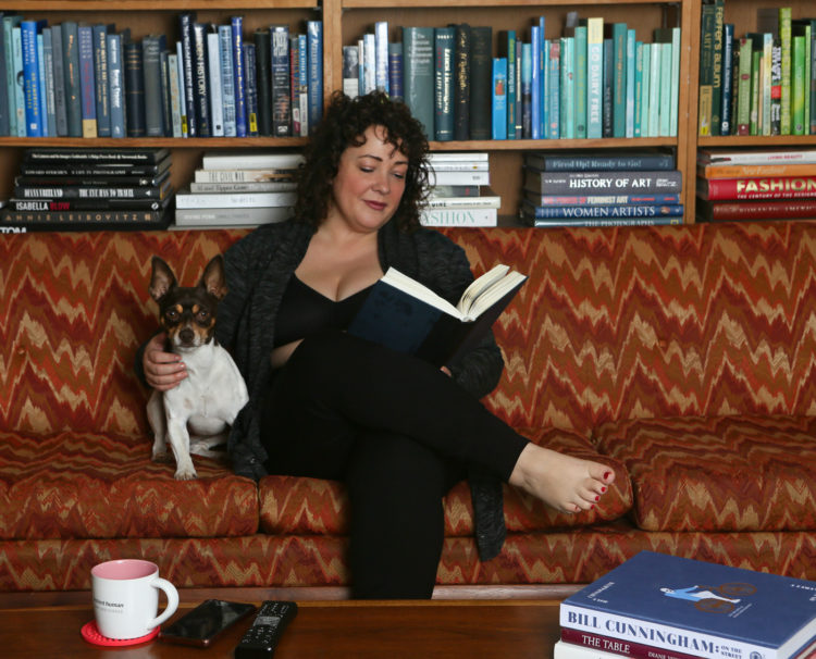 Alison of Wardrobe Oxygen sitting on her living room sofa with her dog, reading a book. She is wearing a Soma wireless bra under a cardigan with black leggings.