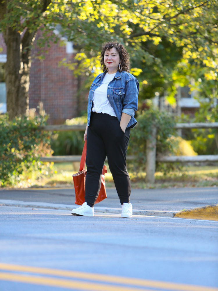 woman in a denim jacket and black knit joggers crossing the street