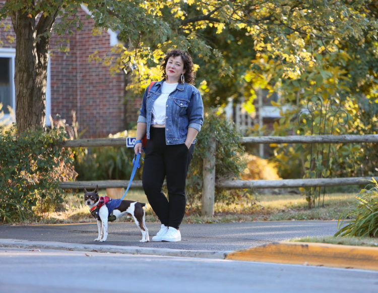 woman in a denim jacket and black knit joggers crossing the street