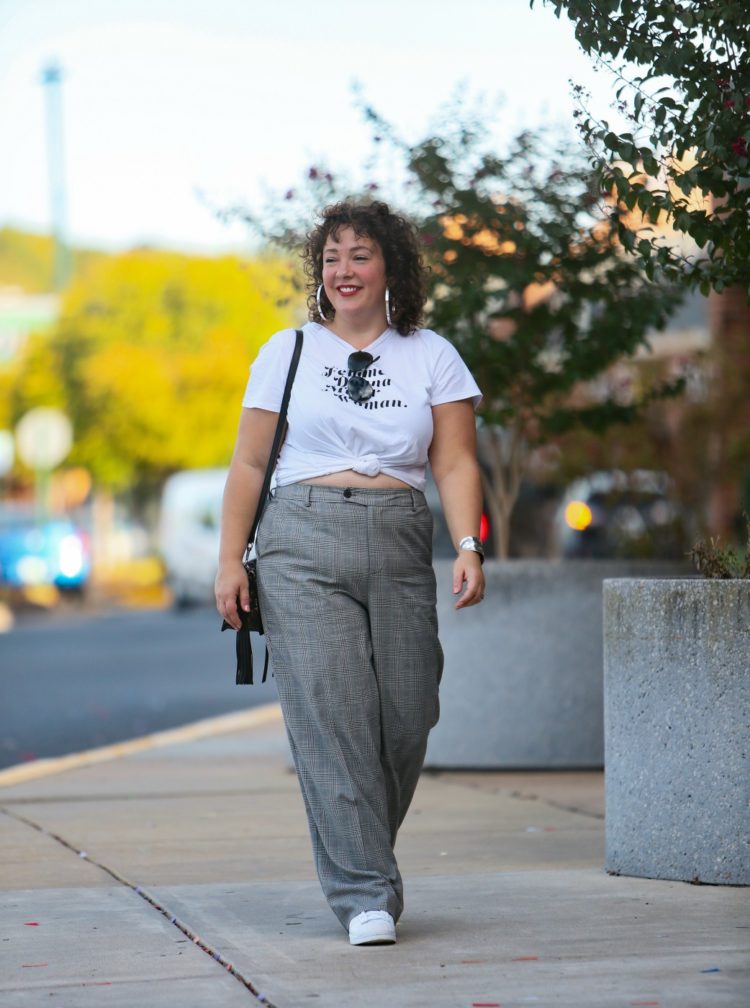 woman in wide leg gray pants and a white t-shirt knotted to show part of her stomach