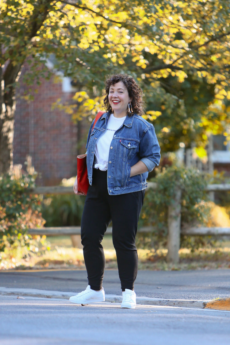 woman in a denim jacket and black knit joggers crossing the street