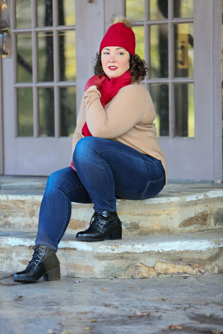 woman in camel cashmere sweater and jeans sitting on a stone step