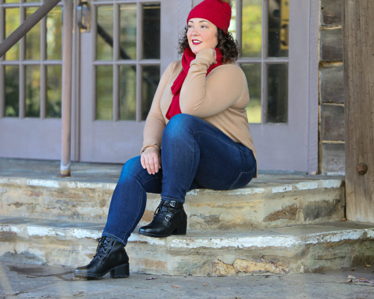 woman in camel cashmere sweater and jeans sitting on a stone step