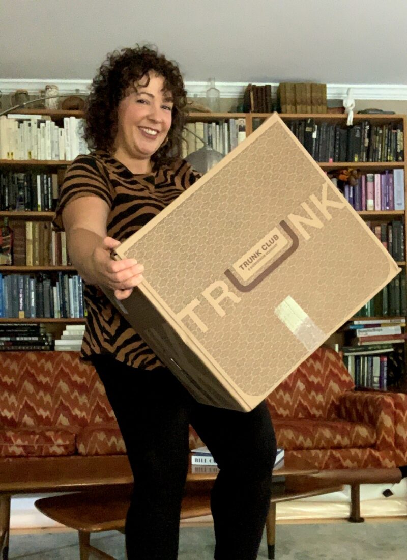 image of woman smiling while holding a large cardboard box that says Trunk Club on it