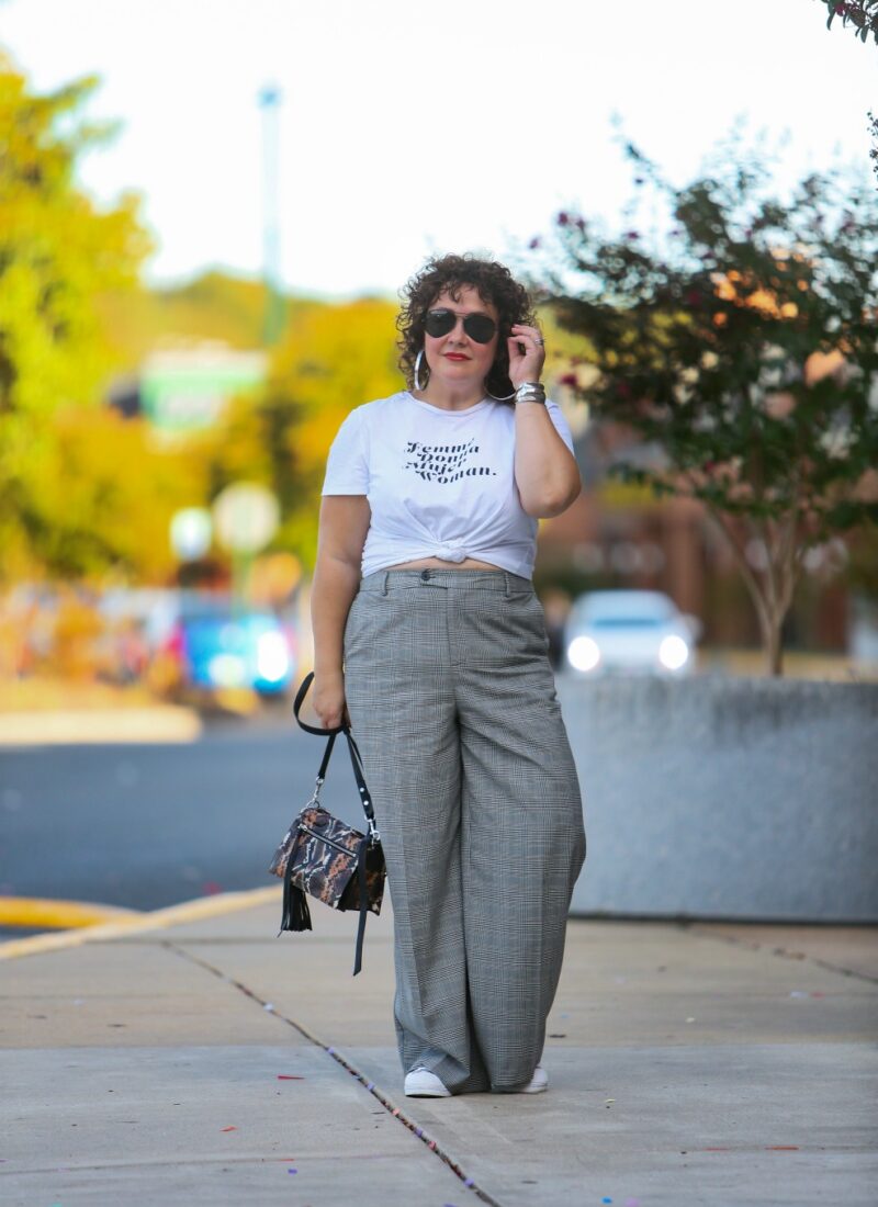 woman in wide leg gray pants and a white t-shirt knotted at her waist